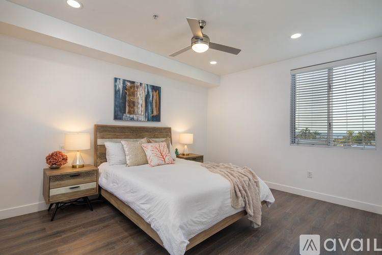 A bedroom with a large bed, a ceiling fan, and a painting on the wall.
