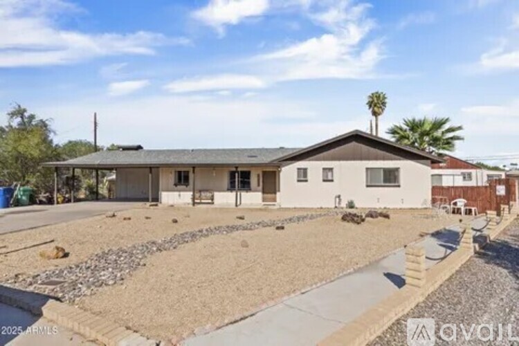 A house with a gravel driveway and a palm tree in the background.