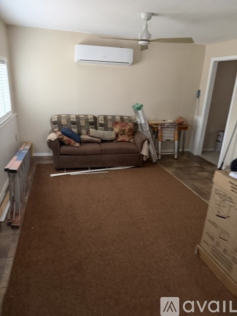 A living room with a couch and a fan on the ceiling.