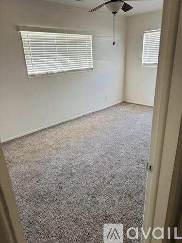 A room with a carpeted floor and a ceiling fan.