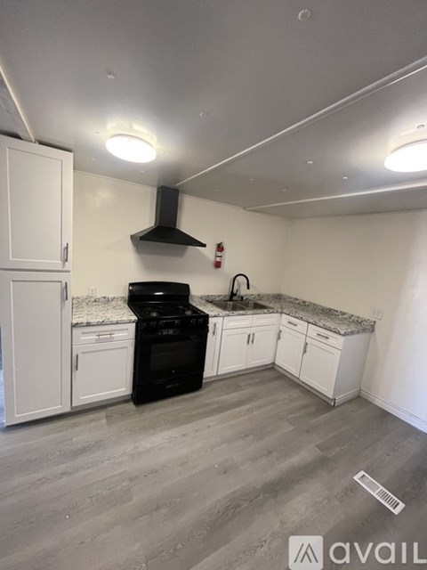 A kitchen with a black stove top oven and white cabinets.