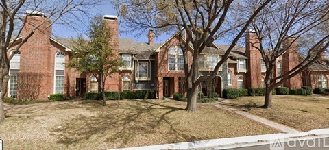 A large red brick house with a tree in front.