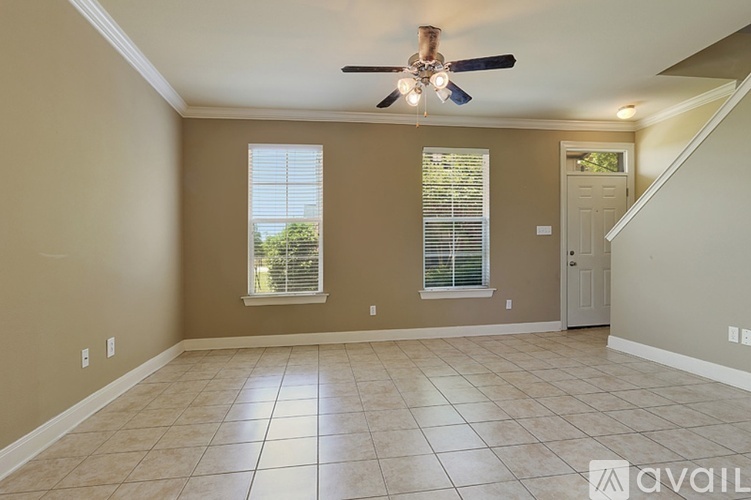 A spacious room with a ceiling fan and tiled flooring.