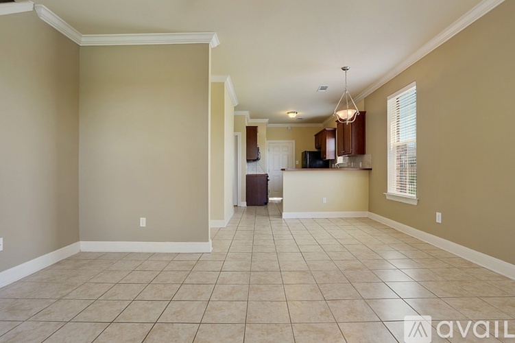 A spacious living room with beige walls and tiled flooring.