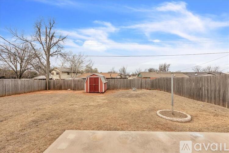 A backyard with a red shed, a fence, and a playground set.