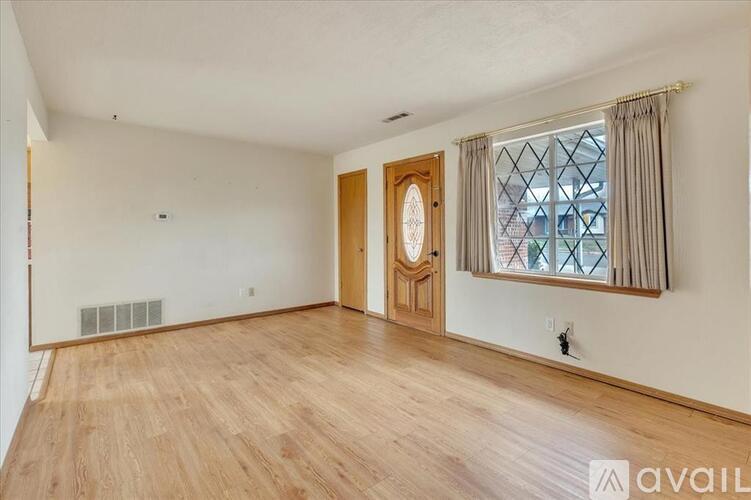 A room with wooden flooring and a large window with a view of a building outside.