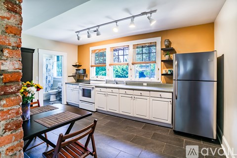 A kitchen with a black fridge and a table with a vase of flowers on it.