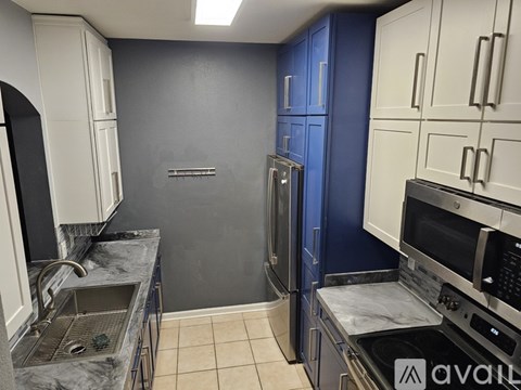 A kitchen with white cabinets and a blue wall.