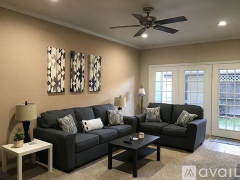 A living room with two couches, a ceiling fan, and a table with a plant on it.
