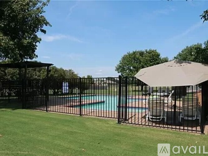 A black fence surrounds a pool with a patio umbrella.