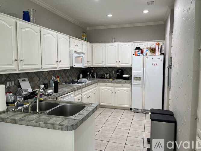 A kitchen with white cabinets and a white fridge.