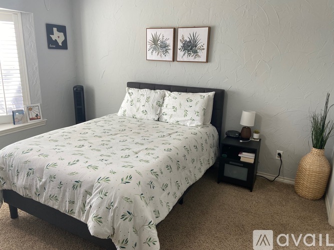 A bedroom with a bed, nightstand, and two framed pictures on the wall.