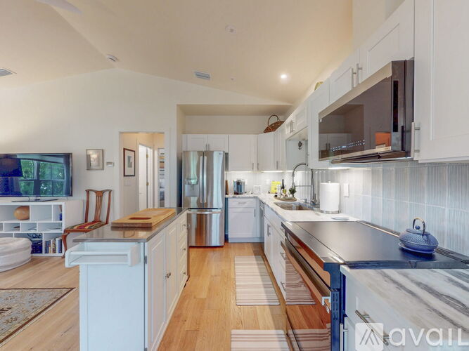 A modern kitchen with white cabinets and a wooden floor.