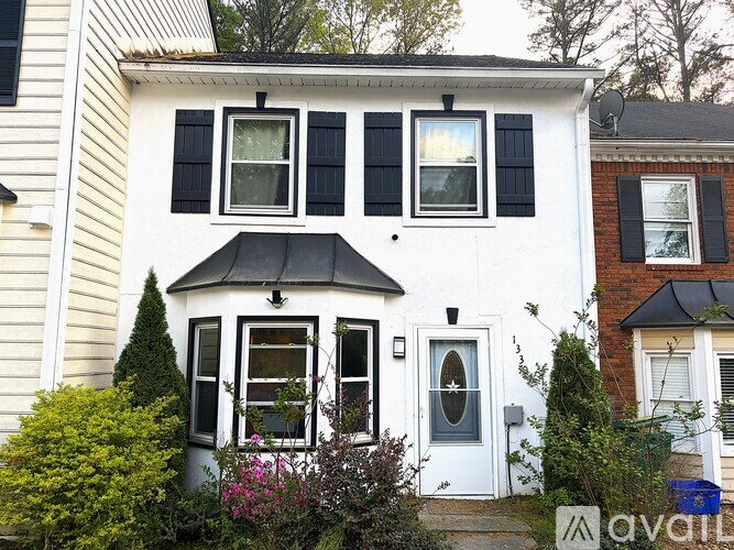 A white house with a black awning and a blue door.