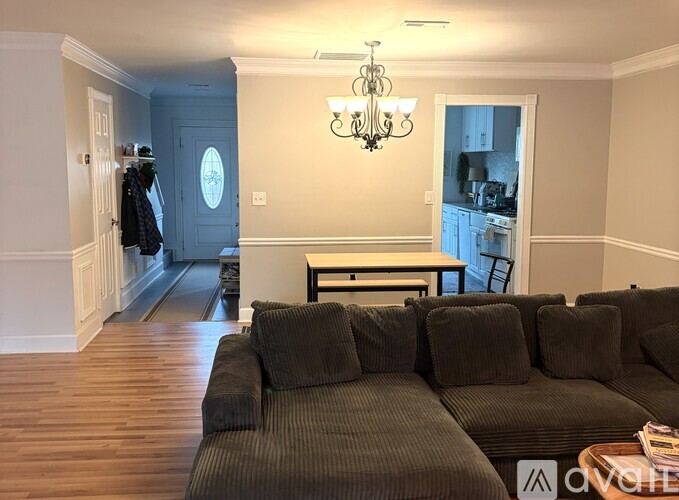 A living room with a grey couch and a chandelier.