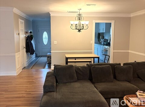 A living room with a grey couch and a chandelier.