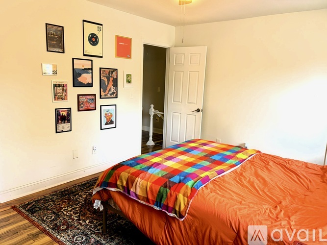 A bedroom with a bed covered in a multicolored blanket and pictures on the wall.