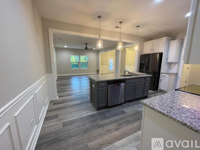 A kitchen with a granite countertop and a stainless steel refrigerator.