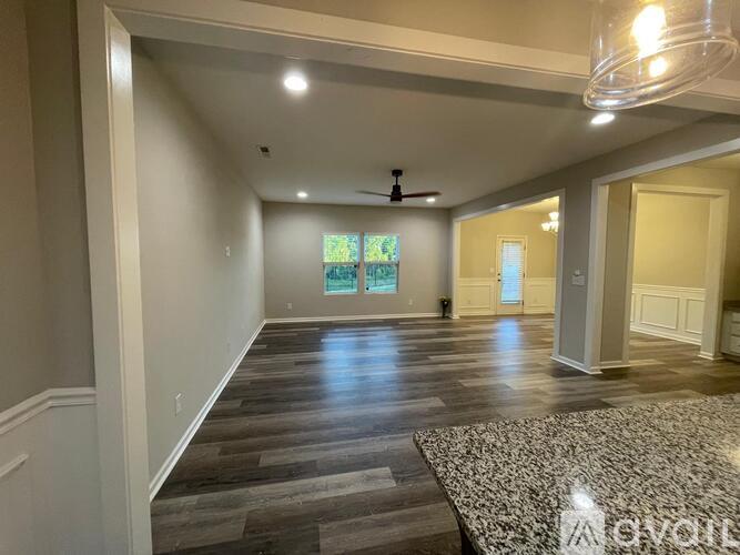 A spacious room with wooden flooring and a ceiling fan.