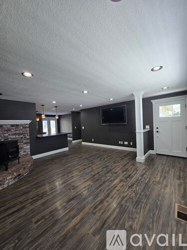 A spacious room with wooden flooring and a fireplace.