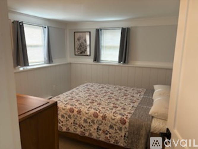 A bedroom with a bed, nightstand and window.