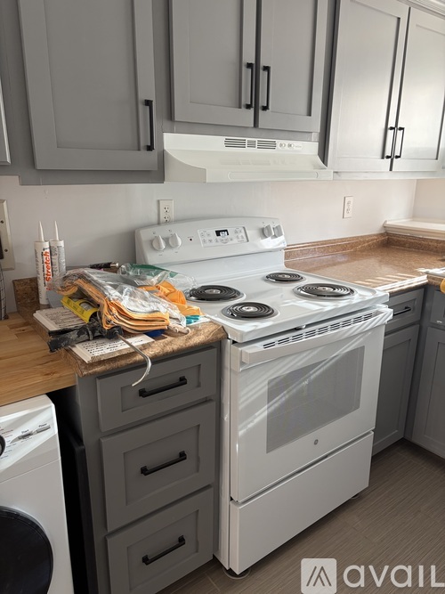 A white stove top oven with a glass door is in a kitchen with a washing machine under a counter.