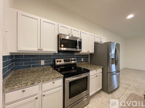 A kitchen with white cabinets and a granite countertop.