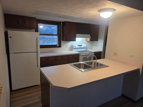 A kitchen with a white fridge and a white counter top.