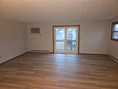 A room with wooden flooring and a sliding glass door.