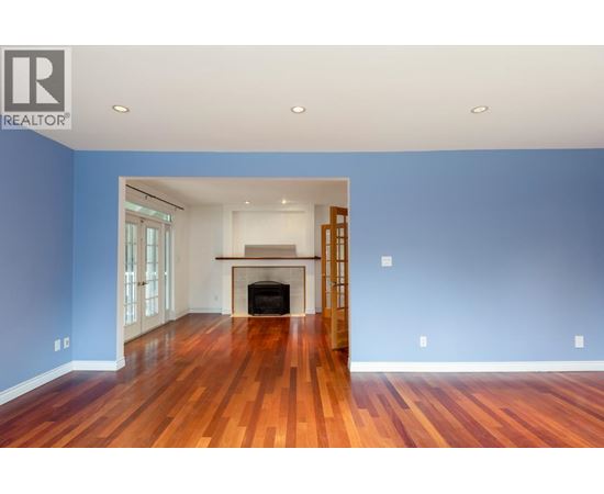 A spacious room with a fireplace and wooden floors.