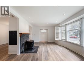 A spacious living room with wood flooring and a fireplace.