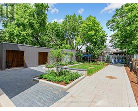 A modern outdoor patio area with a brick patterned walkway and a small garden.