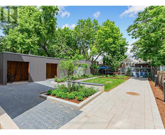 A modern outdoor patio area with a brick patterned walkway and a small garden.