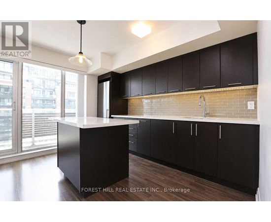 A kitchen with black cabinets and a white island.