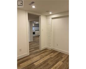 A hallway with wood flooring and white walls.