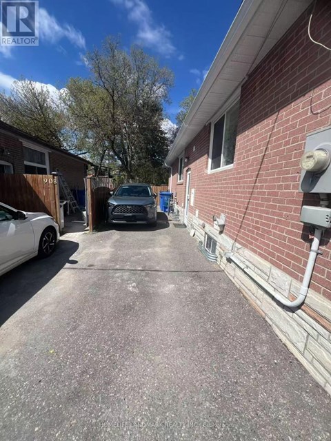 A white car is parked on a driveway next to a brick building.