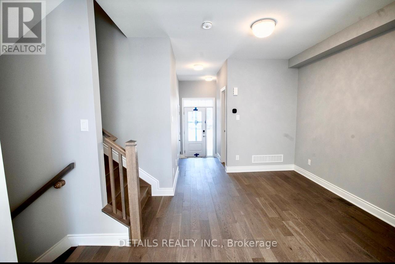 A hallway with wood floors and white walls leading to a door.