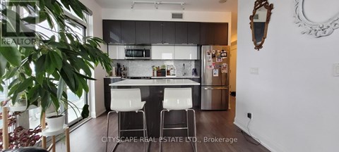 A kitchen with white chairs and a black counter.