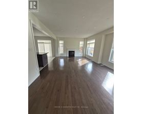 A spacious living room with wood flooring and white walls.