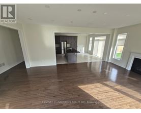 A spacious room with wooden flooring and a large window.