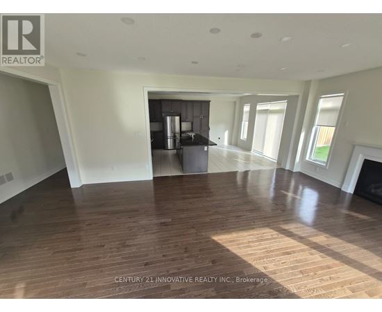 A spacious room with wooden flooring and a large window.