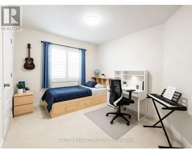 A bedroom with a bed, desk, chair, and a guitar hanging on the wall.