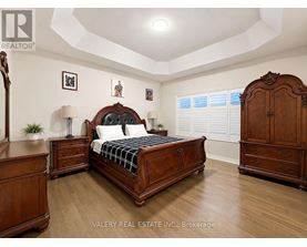 A bedroom with a large bed, wooden furniture, and a framed picture on the wall.