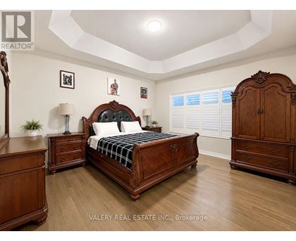 A bedroom with a large bed, wooden furniture, and a framed picture on the wall.