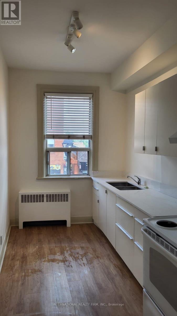 A kitchen with white cabinets and a window with blinds.