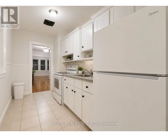 A kitchen with white cabinets and a white refrigerator.