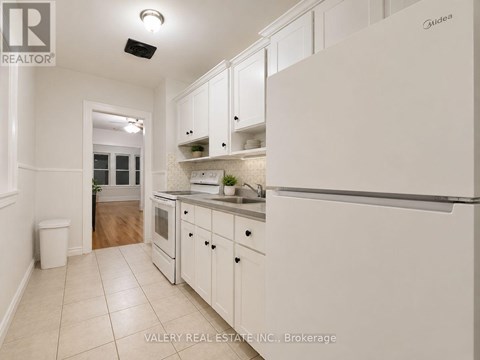 A kitchen with white cabinets and a white refrigerator.
