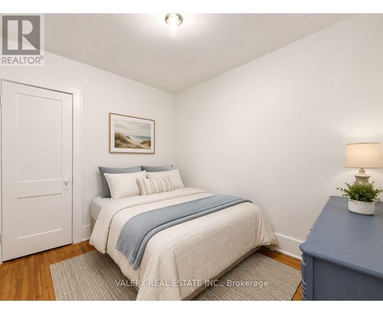 A bedroom with a bed, a lamp, and a painting on the wall.
