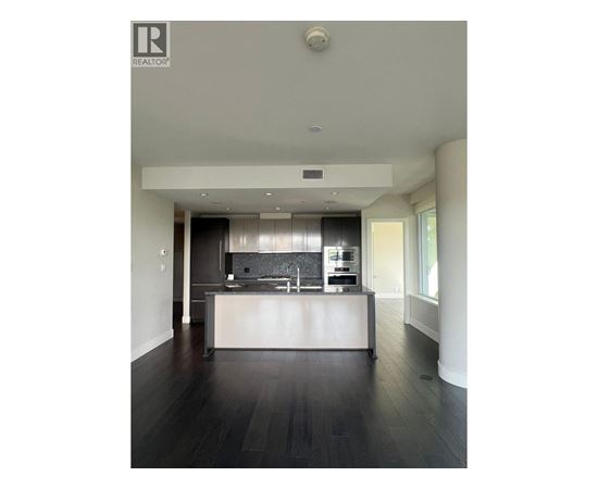 A modern kitchen with dark wood floors and white cabinetry.