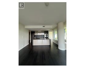 A spacious kitchen with dark wood floors and white walls.